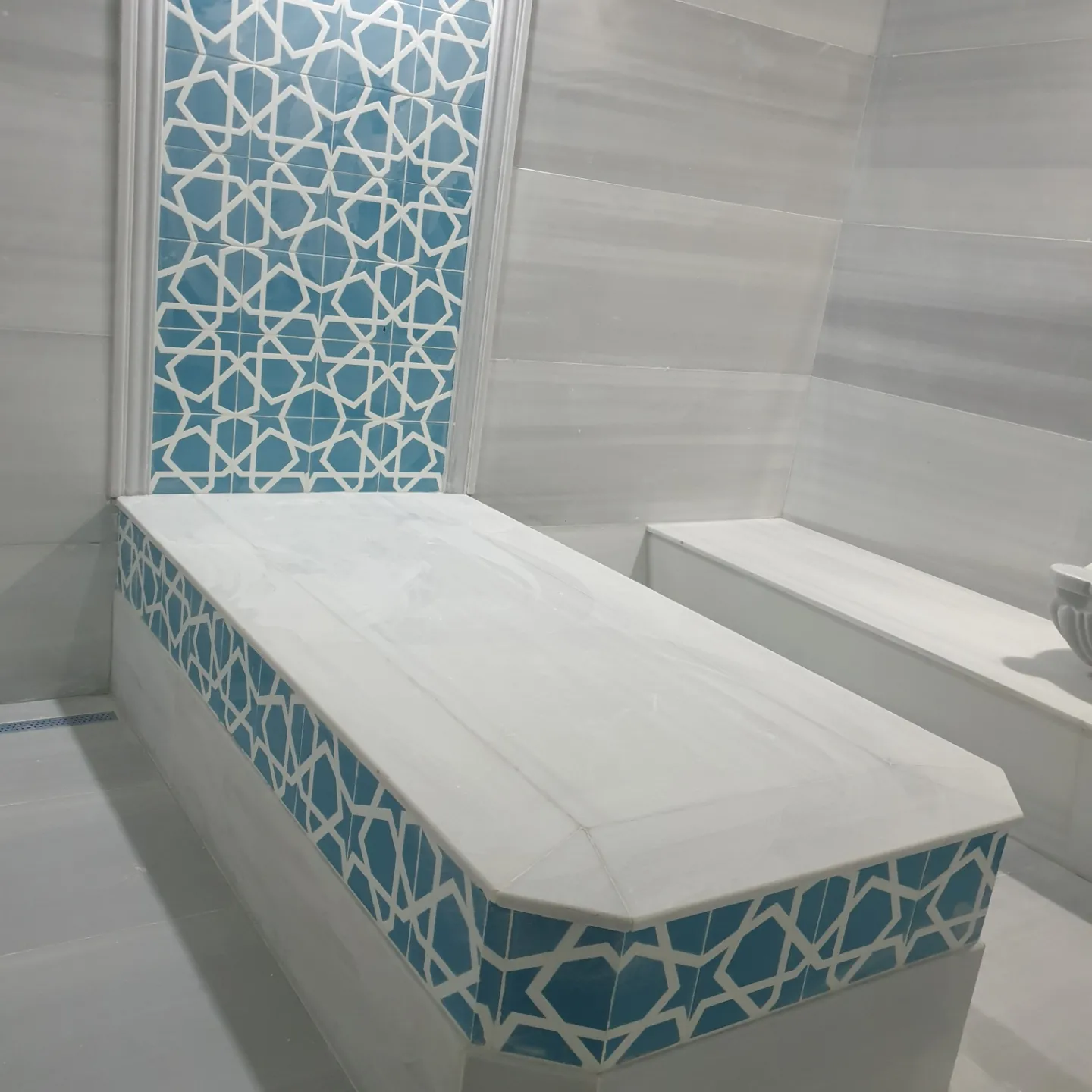 Köşe sekili turkuaz hamam: Geniş mermer seki ve dikey çini pano